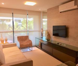 uma sala de estar com uma televisão e um sofá em Carneiros Beach Resort - Flat 205-A em Praia dos Carneiros