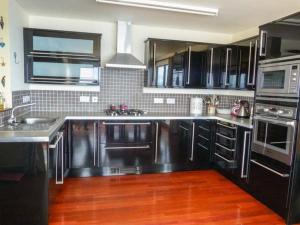 a kitchen with black cabinets and stainless steel appliances at Coast House in Little Gruinard