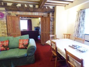 a living room with a table and a green couch at Arllen Fawr in Pen-y-bont-fawr