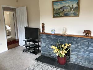 a living room with a brick fireplace with a tv at Trelowarth in St. Agnes
