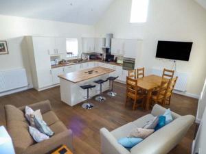 a kitchen and living room with a couch and a table at Ysgubor Newydd in Cemaes Bay
