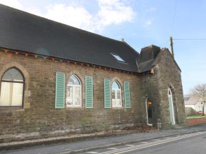a brick building with green shuttered windows and a black roof at No 1 Church Cottages in Llanelli