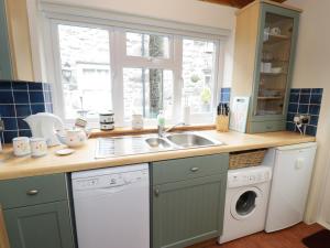 a kitchen with a sink and a washing machine at Cae Tanws Bach in Dolgellau