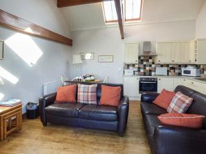 a living room with a leather couch and a kitchen at Y Wennol in Holyhead