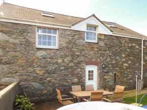 uma casa de pedra com uma mesa e cadeiras em frente em Bran Goesgoch em Holyhead