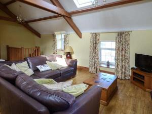 uma sala de estar com um sofá de couro e uma televisão em Bran Goesgoch em Holyhead