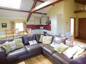um sofá de couro castanho numa sala de estar com uma cozinha em Bran Goesgoch em Holyhead