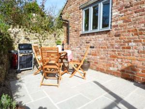 a patio with two chairs and a table and a brick building at Goosepond in Wistanstow