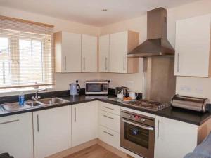 a kitchen with white cabinets and a sink and a microwave at Hakuna Matata in Camber