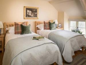 a bedroom with two beds with blankets and pillows at Limecombe in Simonsbath