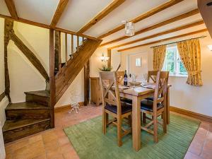 a dining room with a wooden table and chairs at Borrowers Cottage in Condover