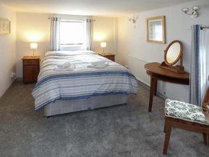 a bedroom with a bed and a mirror and a desk at Fairwater Mill Cottage in Kingsteignton
