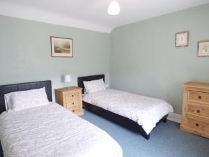 a bedroom with two beds and wooden dressers at Y Bwythyn at Henfaes in Rhydymain