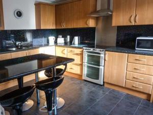 a kitchen with wooden cabinets and a black counter top at Coastal Cottage in Inverallochy