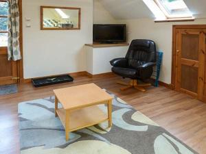 uma sala de estar com uma cadeira preta e uma mesa em Lakefield Apartment em Bearnock