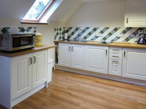 uma cozinha com armários brancos e um micro-ondas em Lakefield Apartment em Bearnock