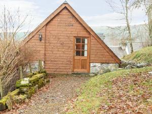 a small house with a wooden door on a hill at Lakefield Apartment in Bearnock