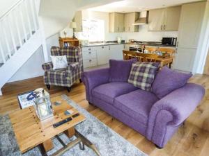 een woonkamer met een paarse bank en een tafel bij Gwdihw in Ifton Heath