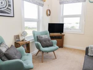 a living room with two chairs and a television at Oak Lodge in Cromer