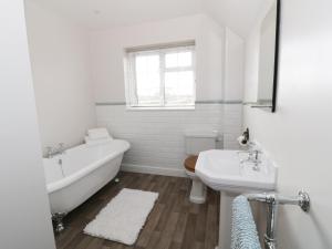 een witte badkamer met een bad en een wastafel bij Glencoe Cottage in Broadway