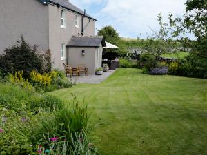 a garden with a house and a table and chairs at Waingate Cottage in Cark