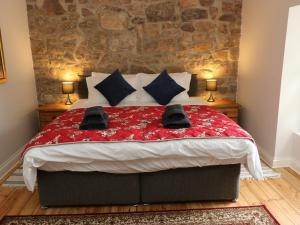 een slaapkamer met een bed met een rood dekbed en 2 lampen bij Riber View in Matlock