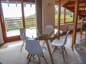 Skipaflotta في Rhiconich: غرفة طعام مع طاولة زجاجية وكراسي بيضاء