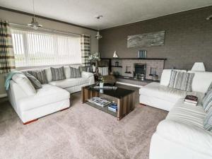 uma sala de estar com sofás brancos e uma lareira em Tritons Reach em Trearddur