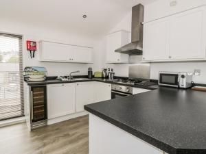a kitchen with white cabinets and a black counter top at 3 Marina View in Pwllheli