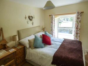 a bedroom with a bed with pillows and a window at Fells Cottage in Sedbergh