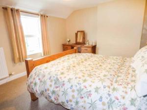 a bedroom with a bed with a floral bedspread and a window at Fran's Cottage in Millington