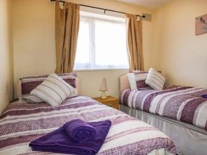 スランディドノにあるMaesdu Cottageの紫と白のシーツが備わる客室のベッド2台