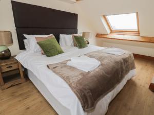 a large bed with white sheets and green pillows at Dumbuie in Haltwhistle