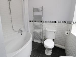 a bathroom with a toilet and a bath tub at Dumbuie in Haltwhistle