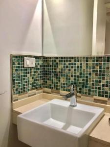 a white sink in a bathroom with green tiles at Apartamento Edificio Unique, Punta del Este in Punta del Este