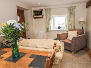 a living room with a couch and a vase of flowers at The Granary Loft in Sunbrick