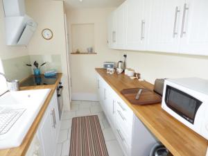 a kitchen with white cabinets and a wooden counter top at The Packing House in Severn Stoke