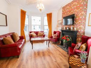 Una sala de estar con muebles rojos y chimenea. en Abbeylands House, en Llandudno