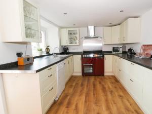 cocina con armarios blancos y horno rojo en Abbeylands House, en Llandudno