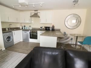 a kitchen with white cabinets and a black leather couch at 5 Windermere in Stourport