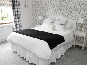 um quarto com uma cama com um edredão preto e branco em Little Beeches em Selattyn