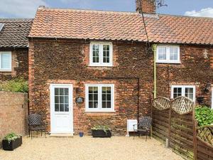 a brick house with chairs and a white door at Meggie's Cottage in Dersingham