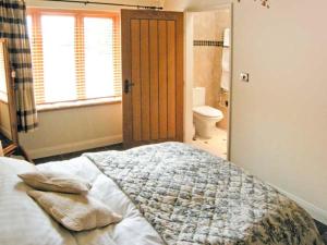 a bedroom with a bed and a bathroom with a toilet at Ginny's Barn in Askham
