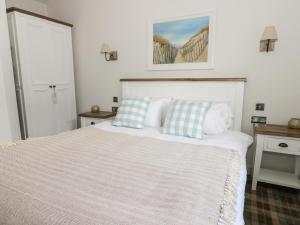 a bedroom with a white bed with two blue pillows at Beach Walk in Reighton