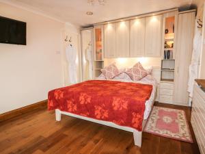 a bedroom with a large bed with a red blanket at The Annex at 60 Rectory Lane in Poringland