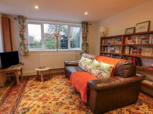 un salon avec un canapé en cuir et des étagères dans l'établissement Sunnyside Garden Cottage, à Husthwaite
