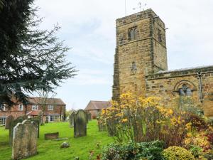 une ancienne église avec une tour d'horloge dans un cimetière dans l'établissement Sunnyside Garden Cottage, à Husthwaite 3 autres photos