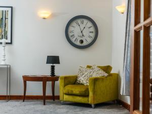 a green chair and a clock on a wall at Nairn in Braunton