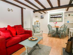a living room with a red couch and a table at Swanfield Cottage in Whitstable