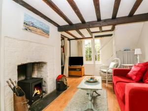 a living room with a red couch and a fireplace at Swanfield Cottage in Whitstable